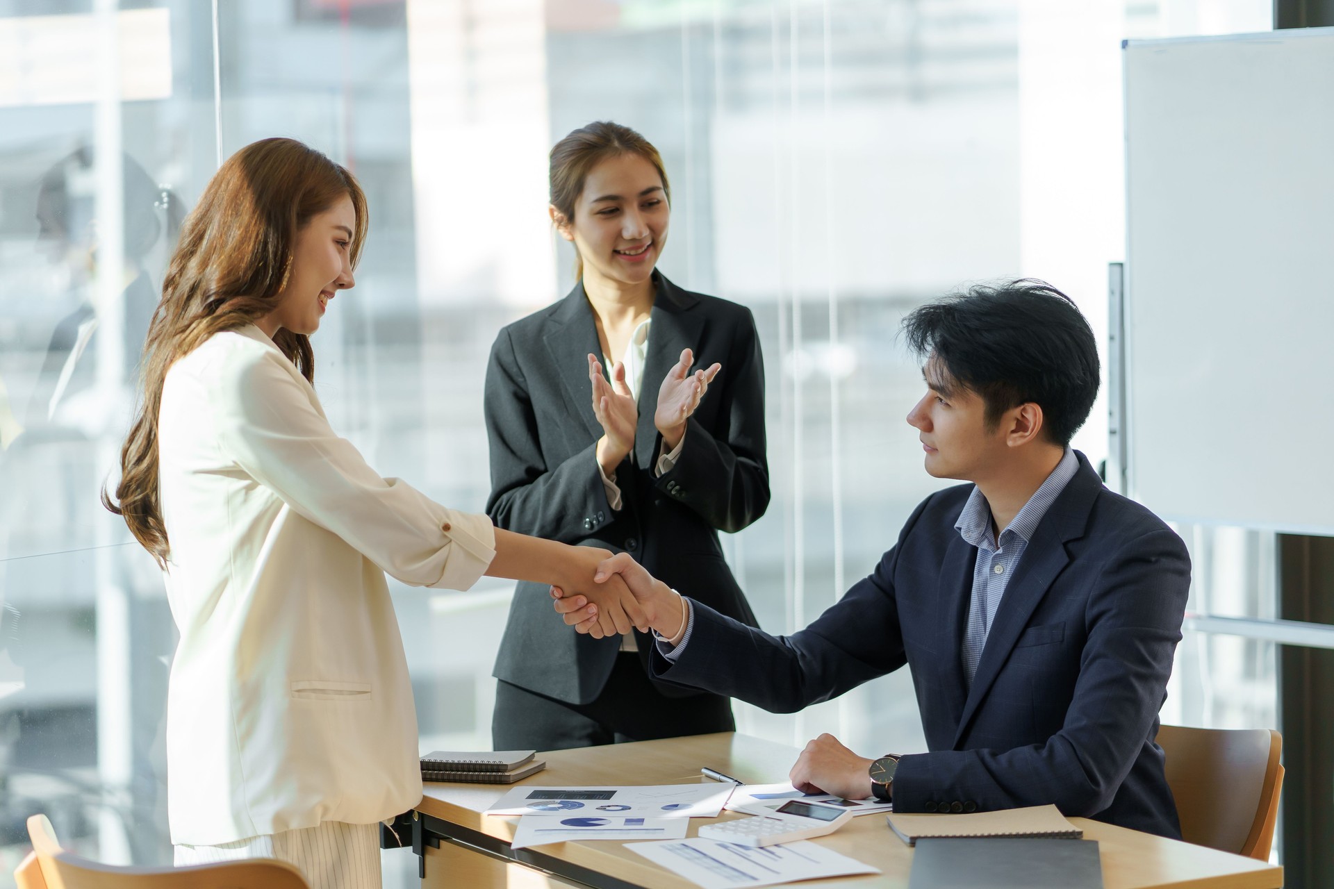 Happy young Asian business people shaking hands to congratulate success. Business executives handshake to congratulate the joint business agreement.